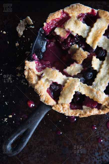 Blueberry and plum pie with a piece cut out