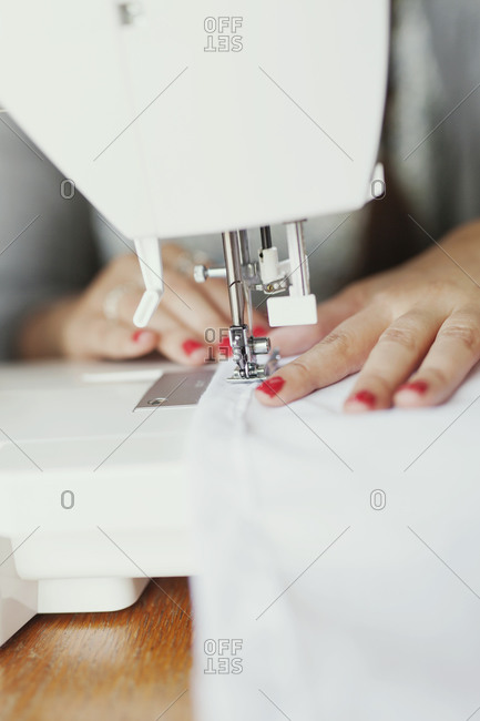 Woman pushing cloth through a sewing machine needle