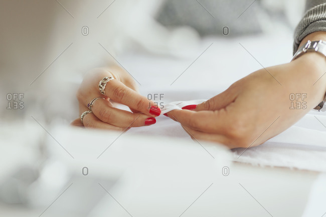 Woman pushing pin through white cloth