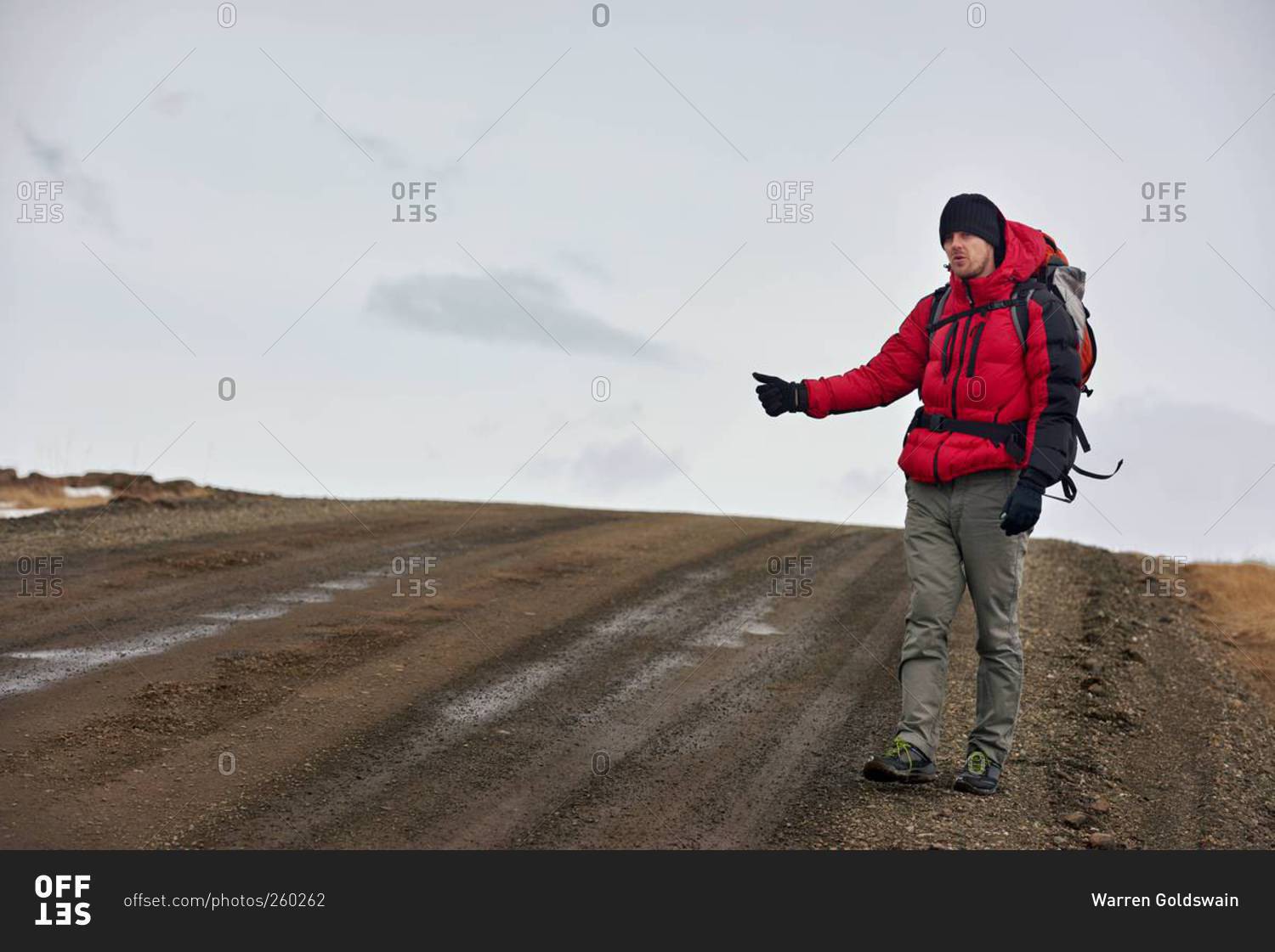 A man hitchhiking for a ride on empty road in Iceland