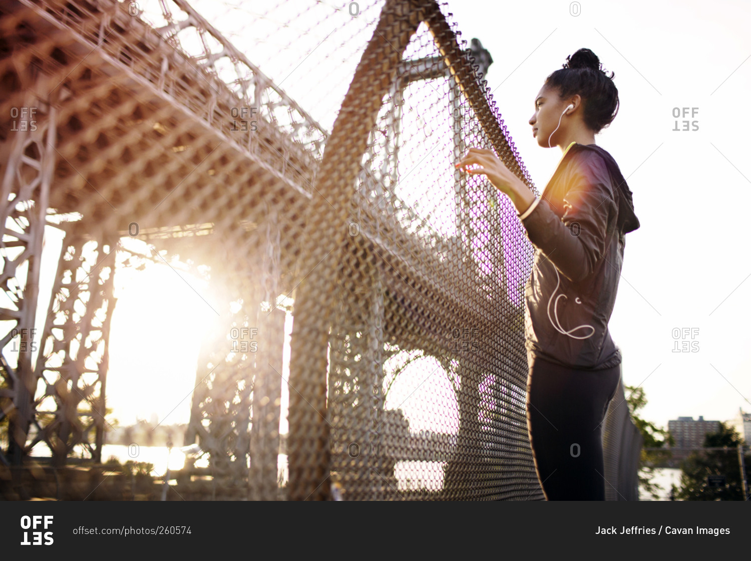Woman in athletic clothes listening to music on bridge