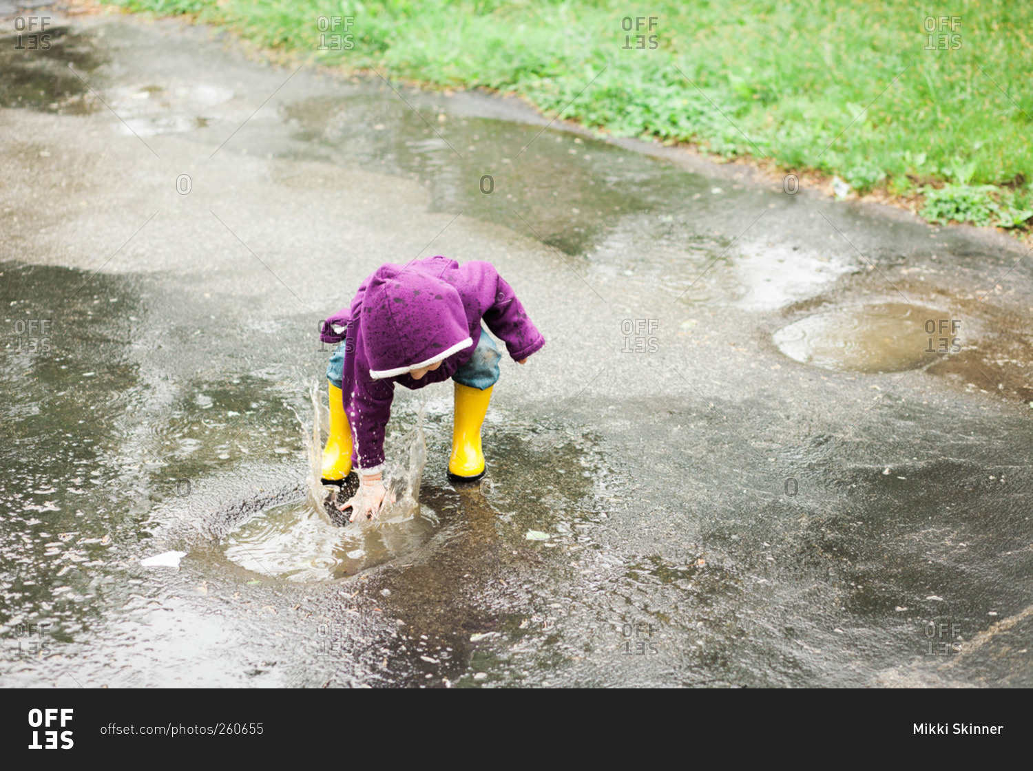 Girl playing in a rain puddle on concrete