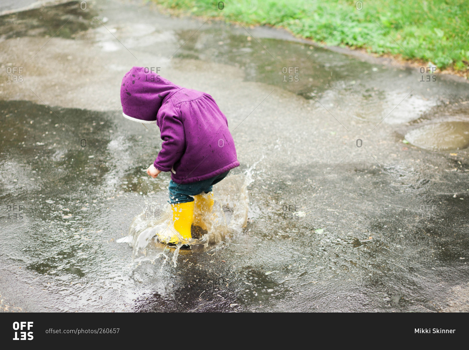 Girl playing in a rain puddle on pavement