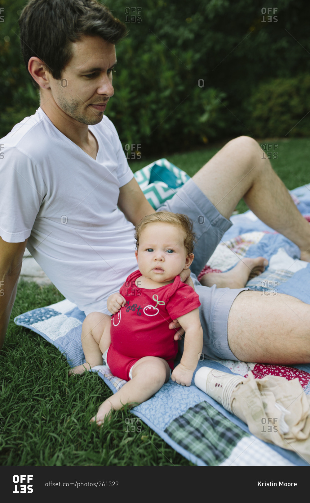 A newborn baby leans against her dad at a family picnic stock photo