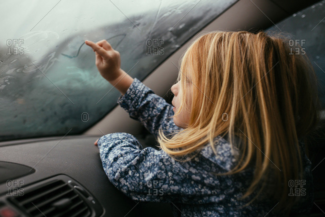 A Girl Draws With Her Finger On A Car Window Stock Photo OFFSET