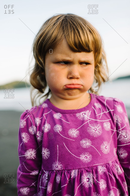 A young girl frowns on the beach
