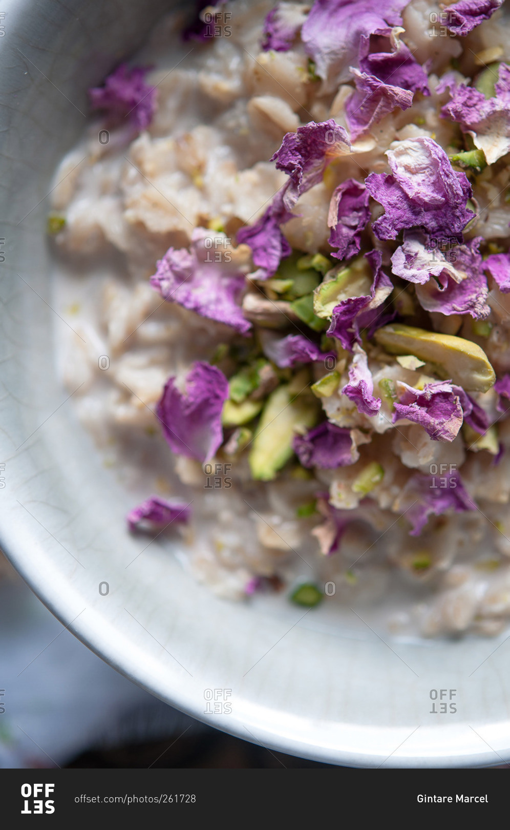 Bowl of oatmeal with purple flowers and pistachios