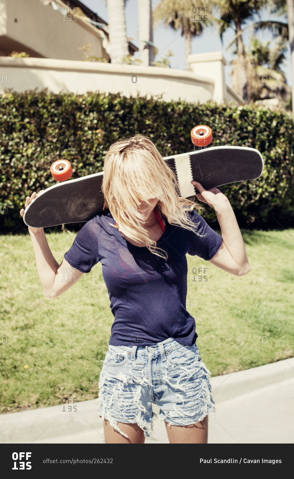 A girl lifts her skateboard in the air
