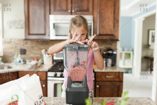 Girl holding down the top of a blender