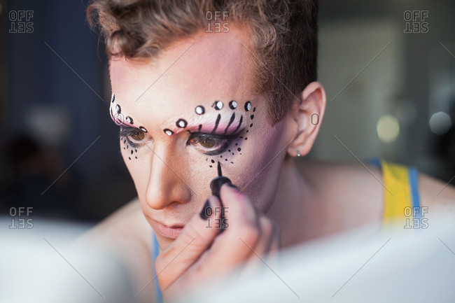 Young man applying drag queen cosmetics