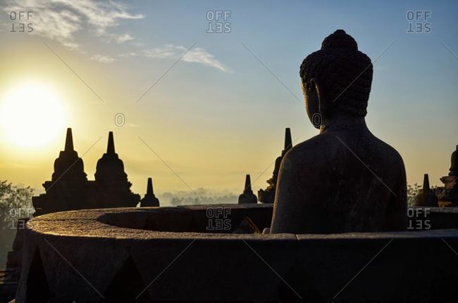Buddha statue and stupa at sunset, Borobudur Temple, Java