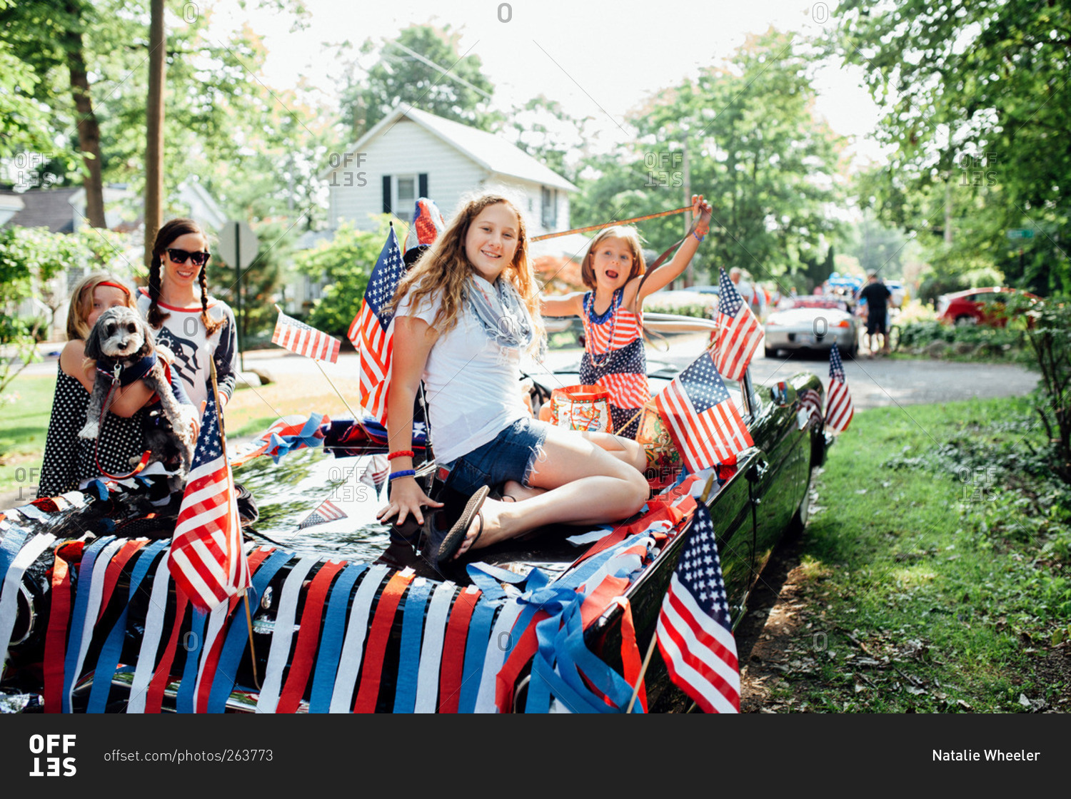 Children playing on the back of a classic car decorated for Independence Day parade