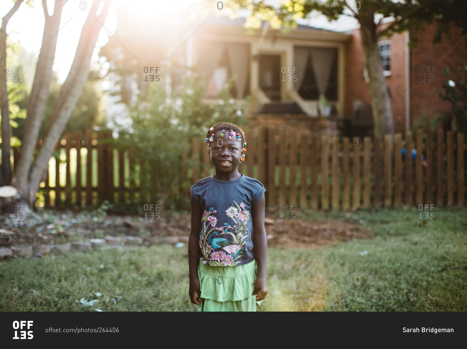 Little girl smiling while standing in sunny yard