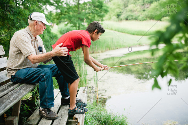 Grandfather helping his grandson reel in a fish