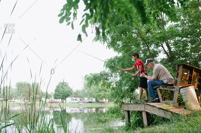 Grandfather teaching boy how to fish