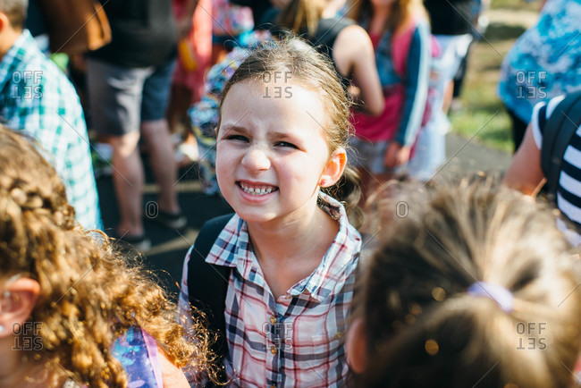 Little girl standing in a crowd grinning at the camera