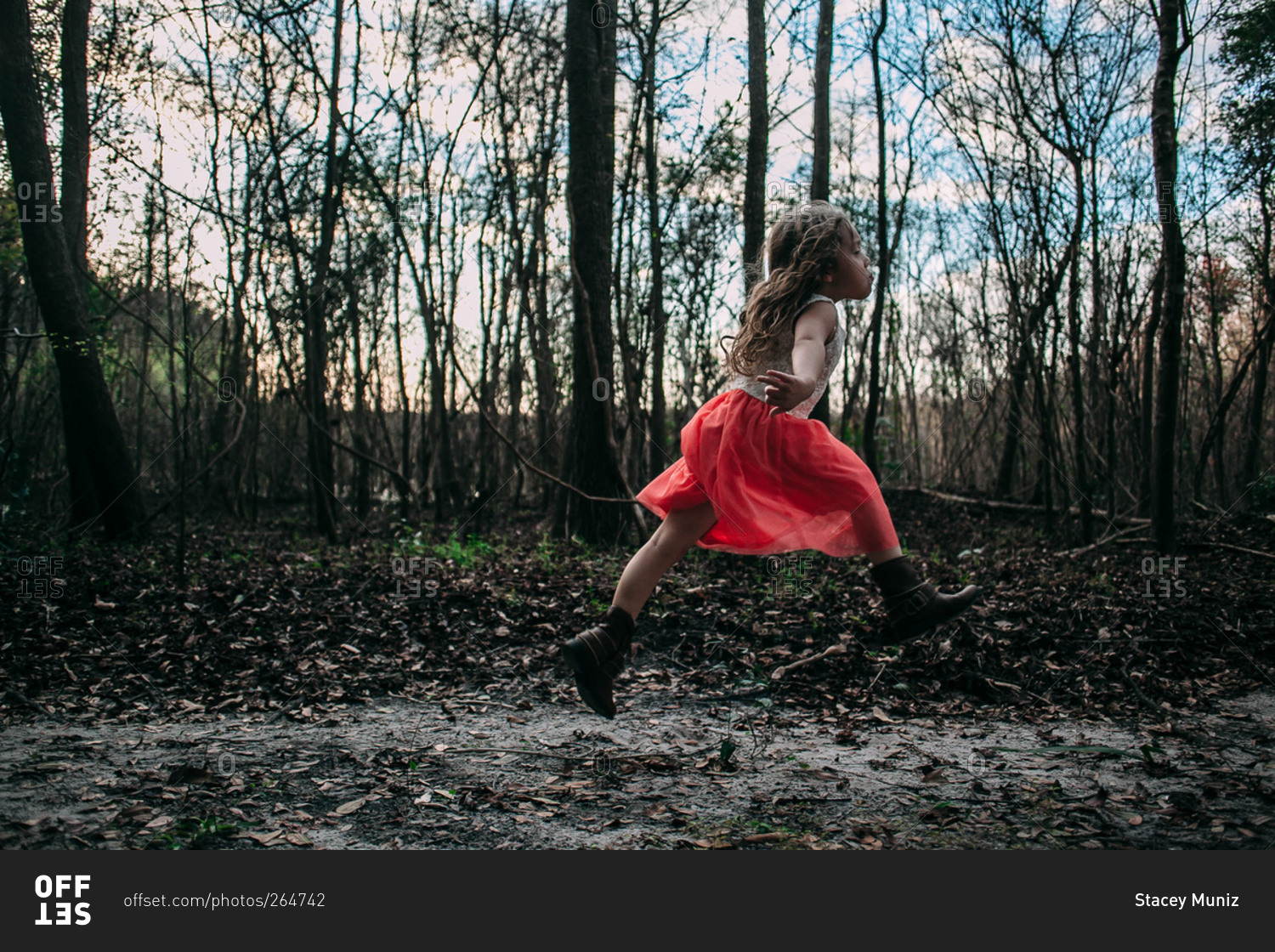 Little girl running through the woods stock photo - OFFSET