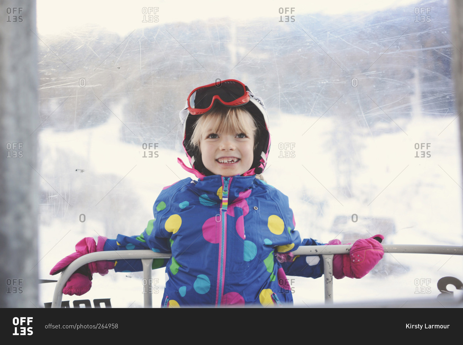 Smiling young girl leaning on railing of ski gondola