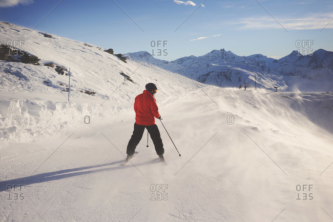 Man skiing on windblown ski trail