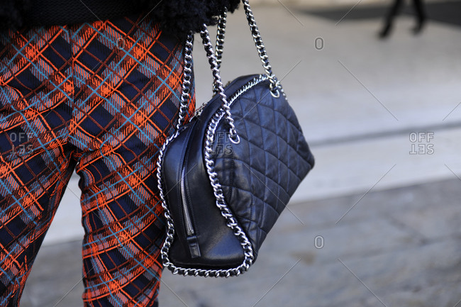 A woman in plaid pants and a quilted leather purse