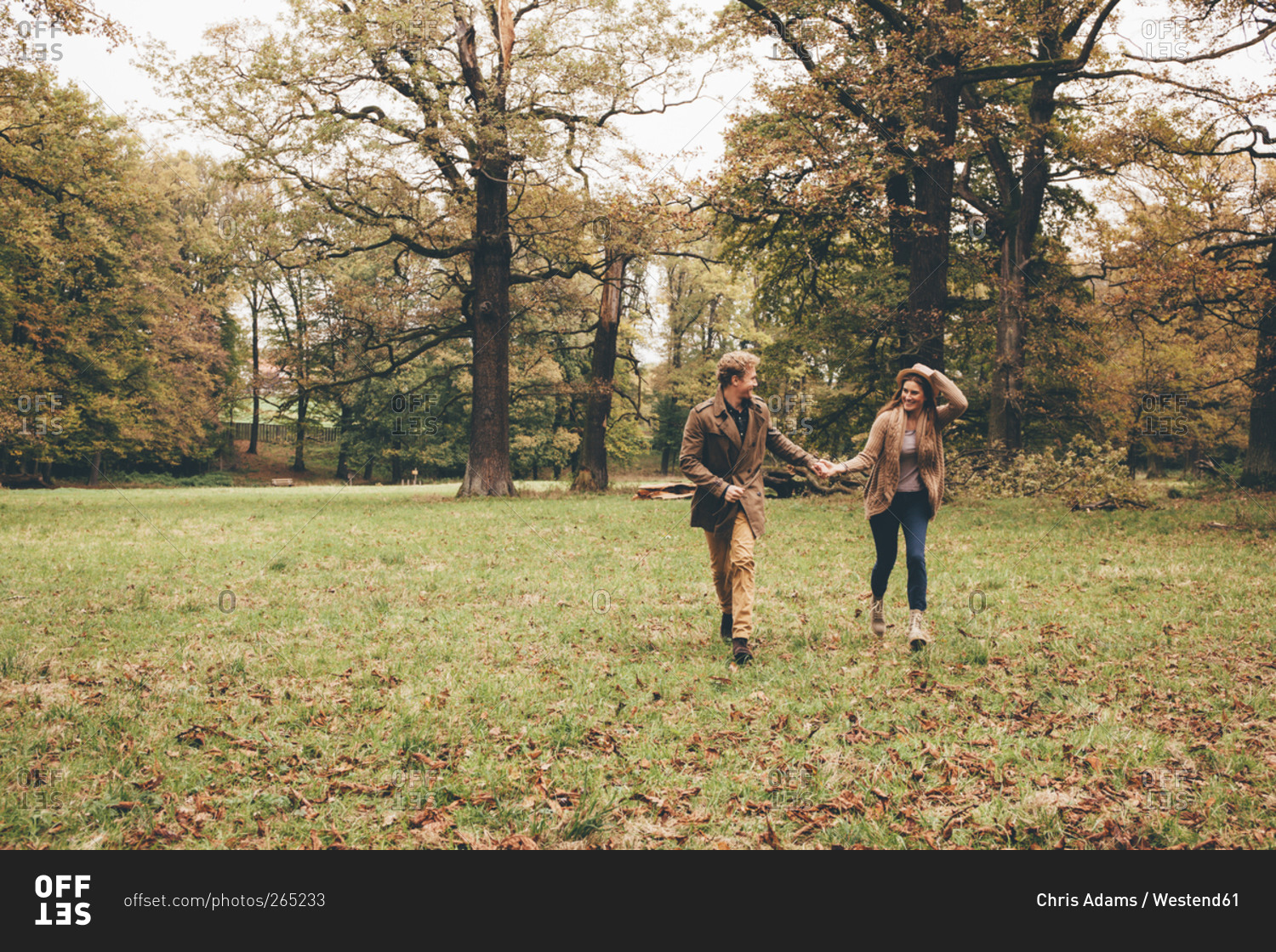 Young couple in love holding hands and running in an autumnal park