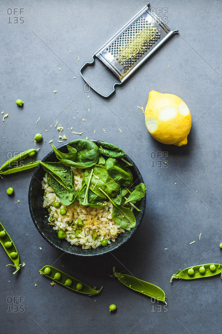 Pea and lemon risotto on stone surface with citrus rind grater