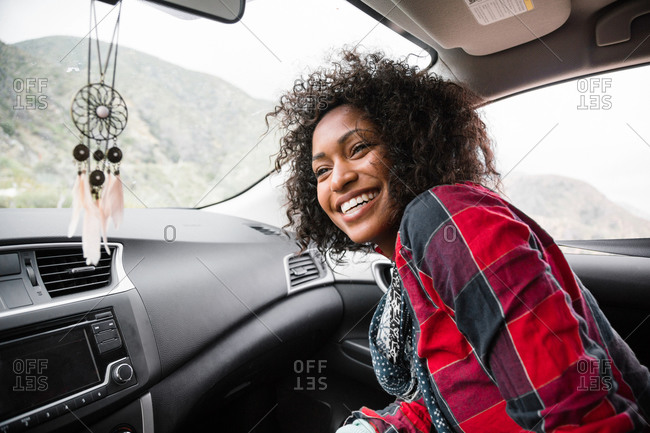 A young woman smiles in the front seat of a car