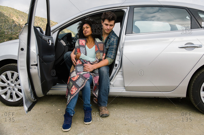 A couple cuddles in the front seat of a parked car