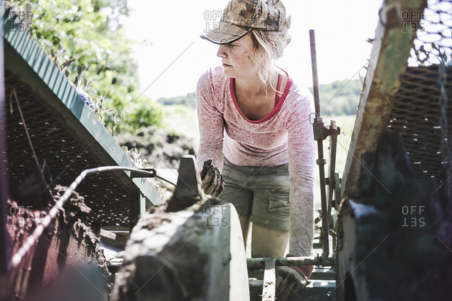 A woman works on farm machinery