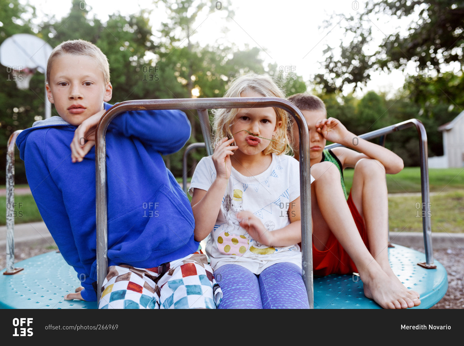 Children on a merry-go-round in a park stock photo - OFFSET