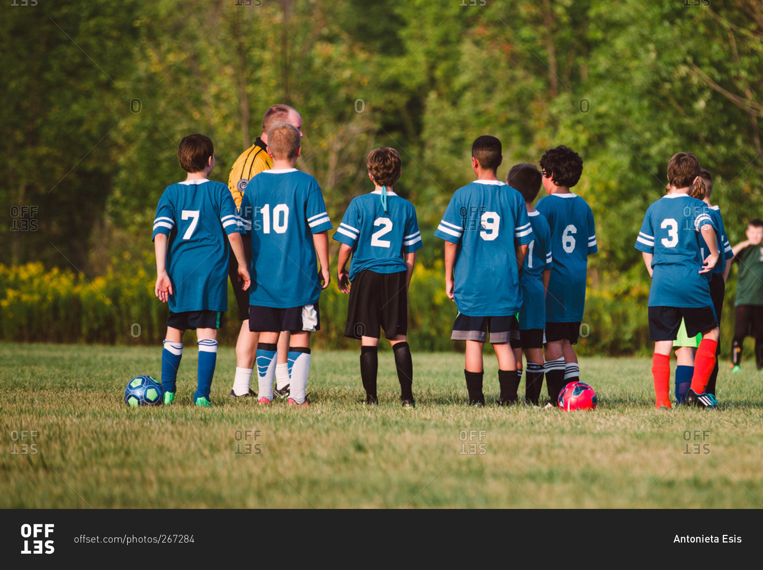 A boys soccer team gathers around their coach