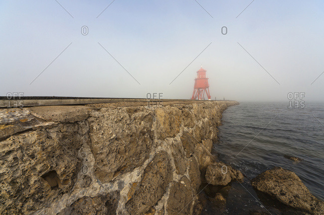 Red lighthouse in the fog on the coast, South Shields, Tyne And Wear, England