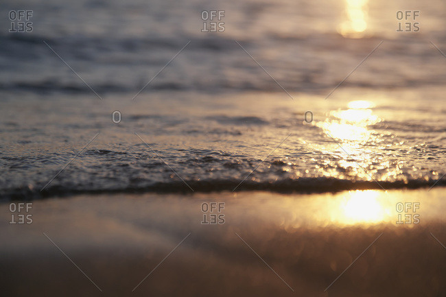 Sunlight reflecting off the water and wet sand at sunset, Honolulu, Oahu, Hawaii, United States Of America