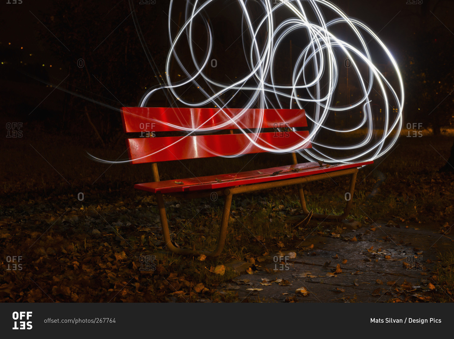 A red park bench in autumn with swirls of white light around it, Locarno, Ticino, Switzerland