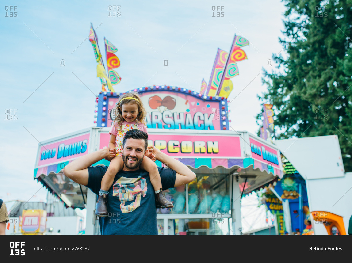 Girl riding on her dad's shoulders at a fair