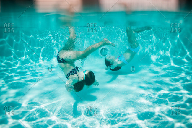 Two girls do somersaults in a pool stock photo - OFFSET