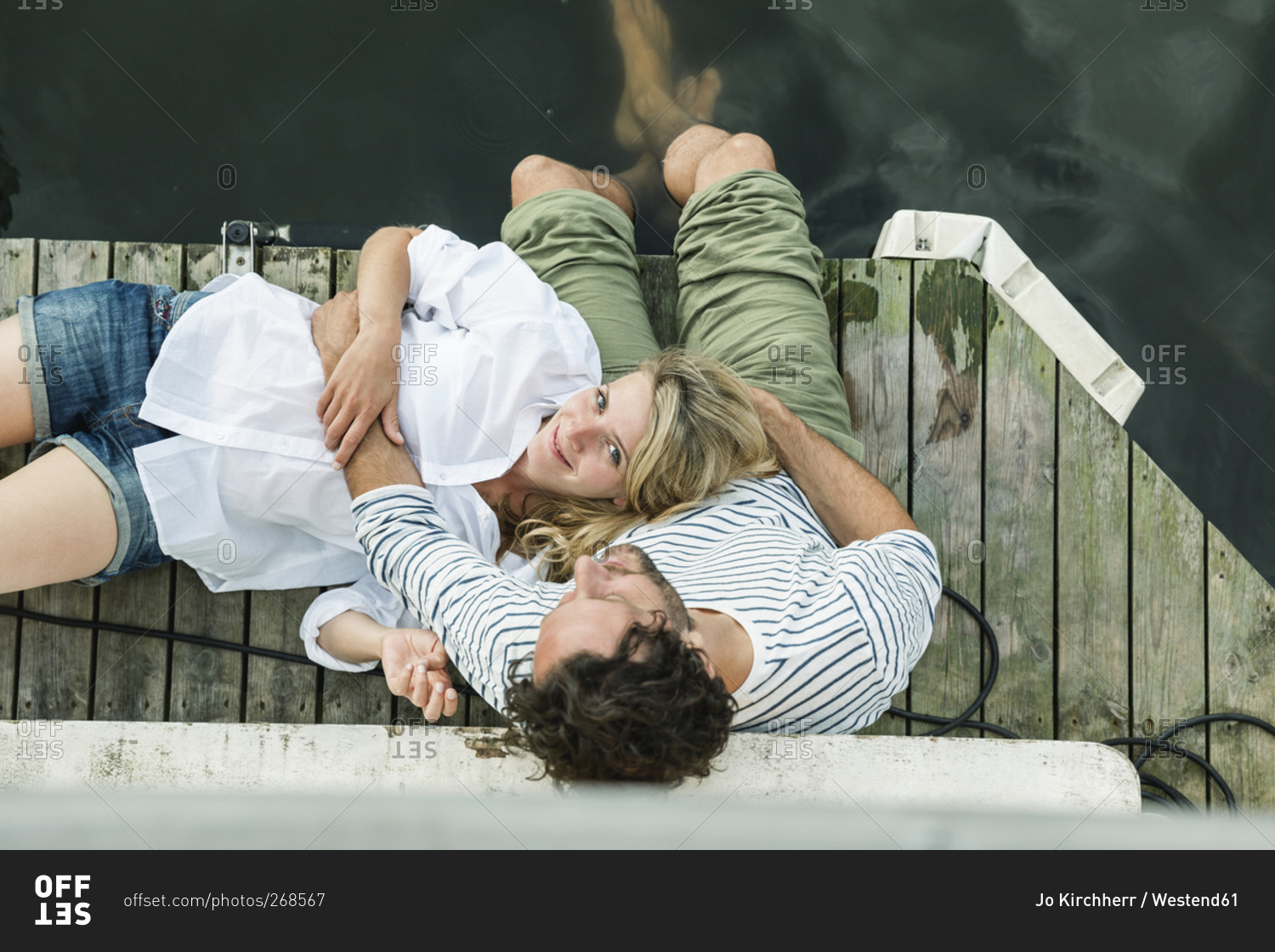 Smiling woman lying on man's lap at the water