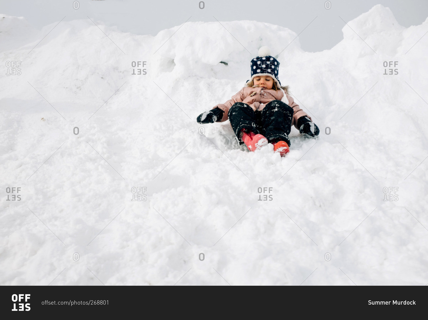 Girl sitting in a snow bank in winter