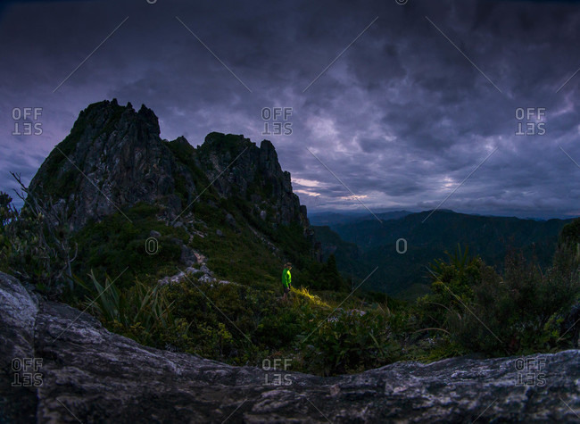 Man standing in a mountainous landscape holding a flashlight