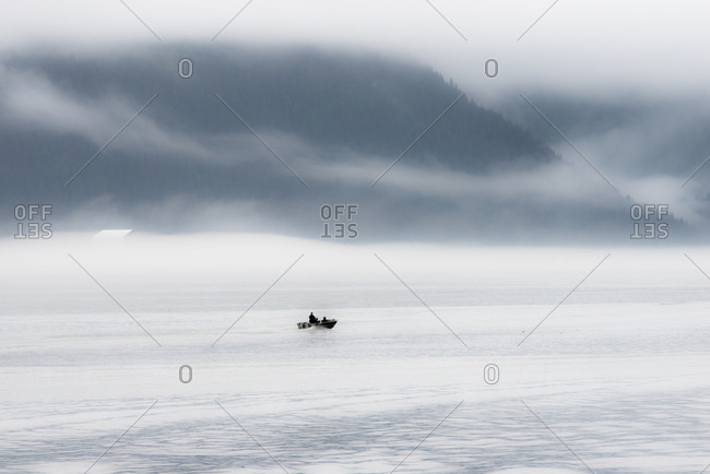 A lone fisher boat heading out in the fog of early morning Seward