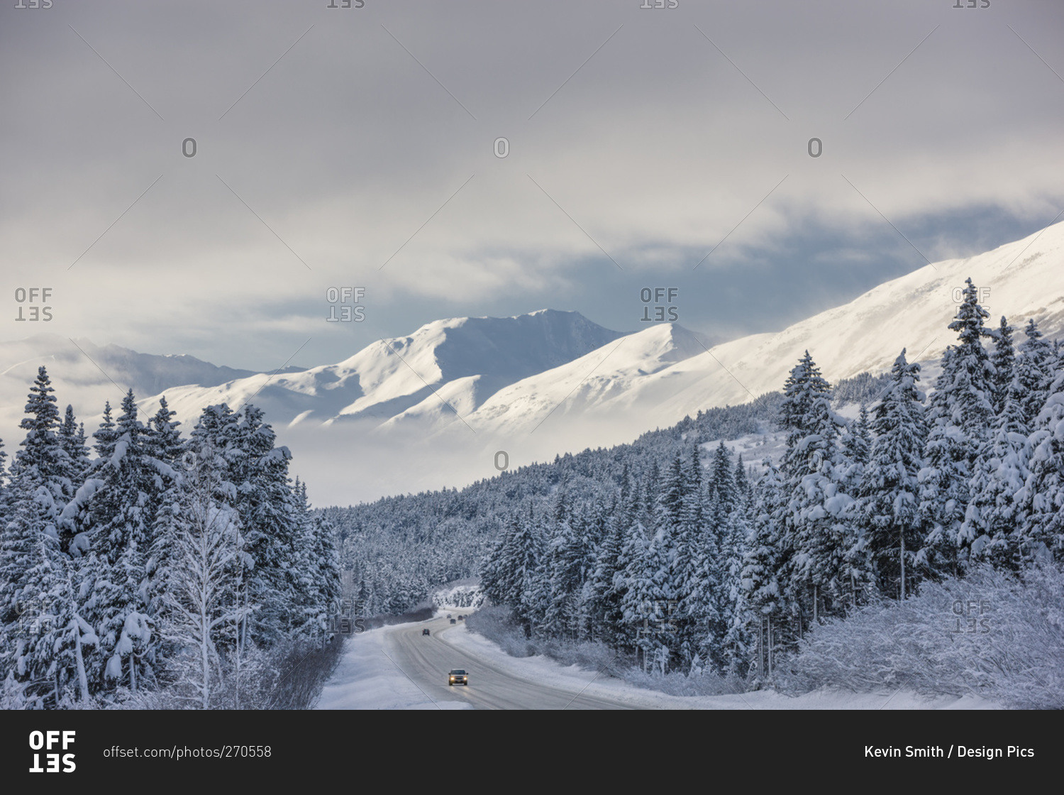 Clouds clearing over Seward Highway from the Kenai Mountains above Turnagain Pass after a winter snow storm, fresh snow in the trees, early morning sun, Turnagain Pass, Chugach National Forest, South-central Alaska, USA