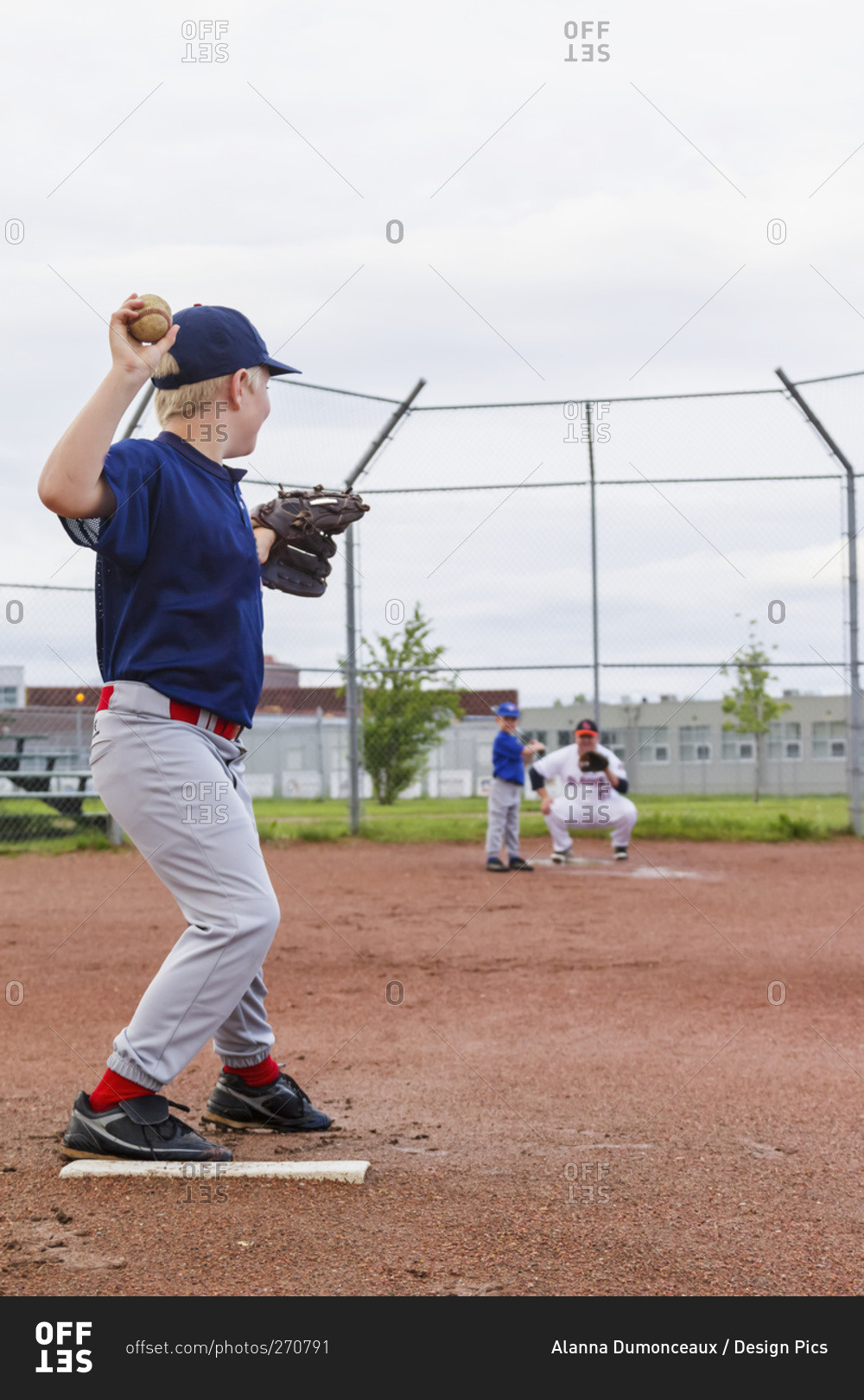 A young boy in his baseball uniform prepares to throw a pitch to his brother at bat, Fort McMurray, Alberta, Canada