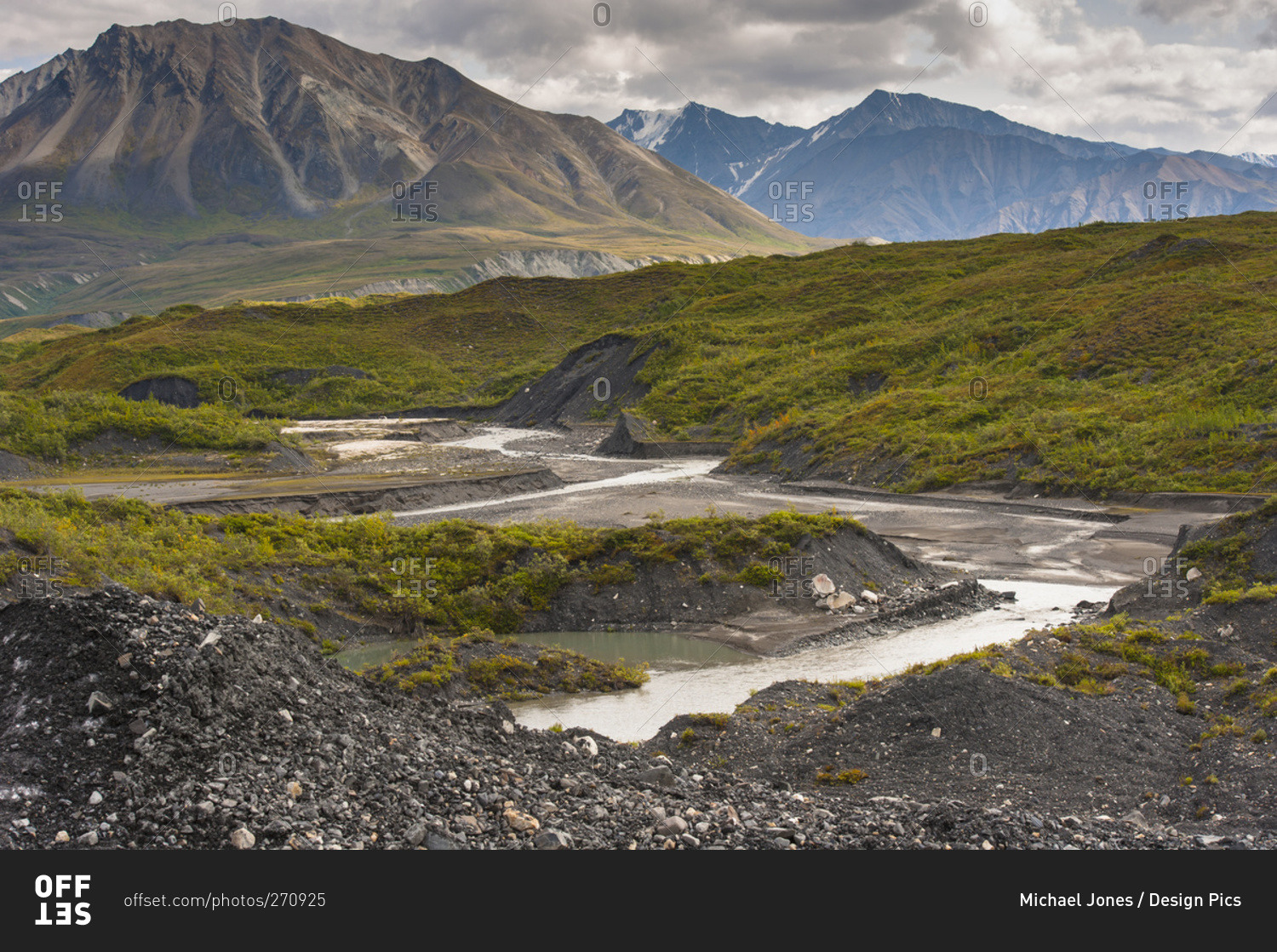 Thorofare River flowing next to the stone and vegetation covered Moldrow Glacier in Denali National Park and Preserve, Mount Eielson and the Alaska Range in the background, Alaska, United States of America