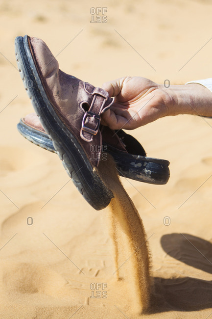 A man empties sand from his sandals at a sand dune near Ezuz, Israel