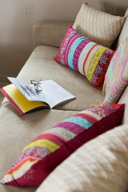 Glasses and book on couch with throw pillows