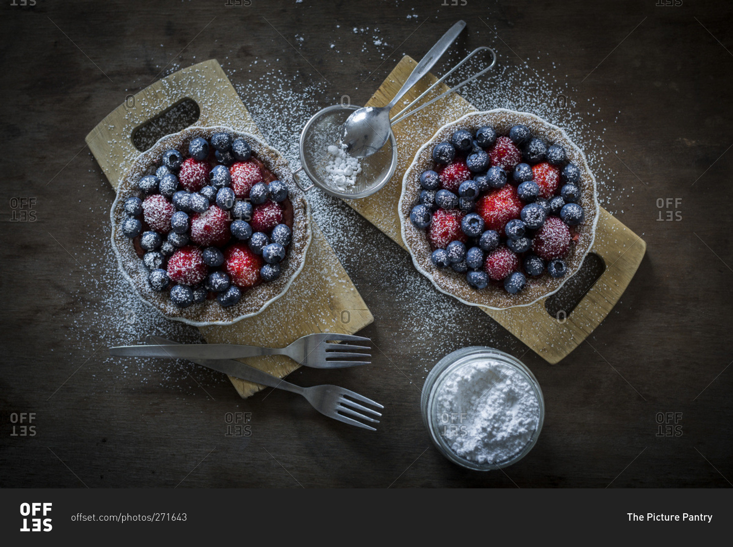 Berry tartlets in baking dishes with powdered sugar
