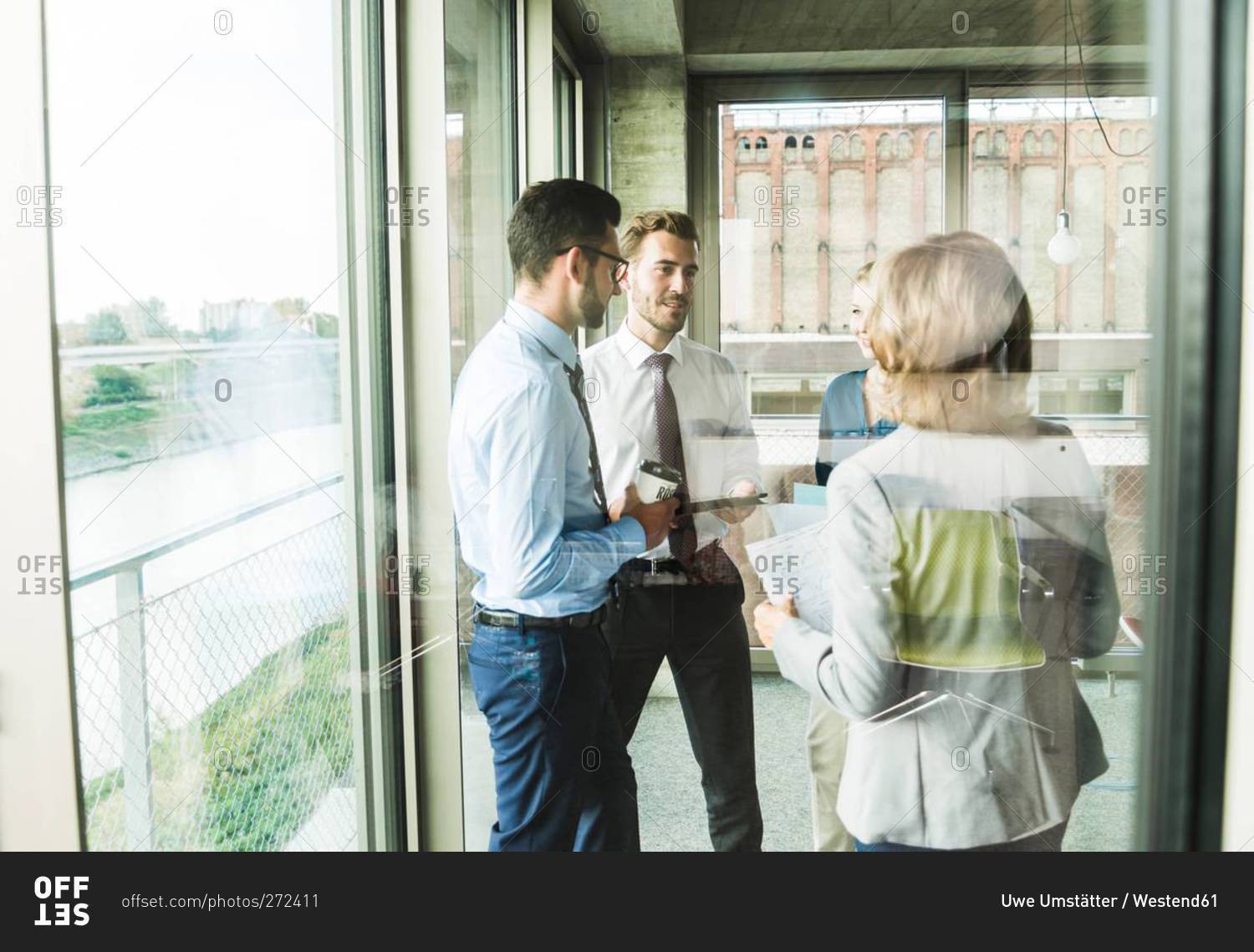 Business people with documents talking at the window