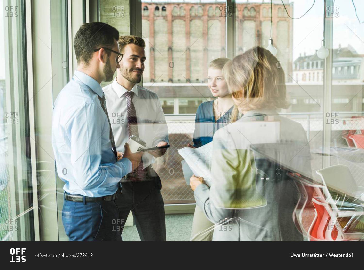 Business people with documents talking at the window