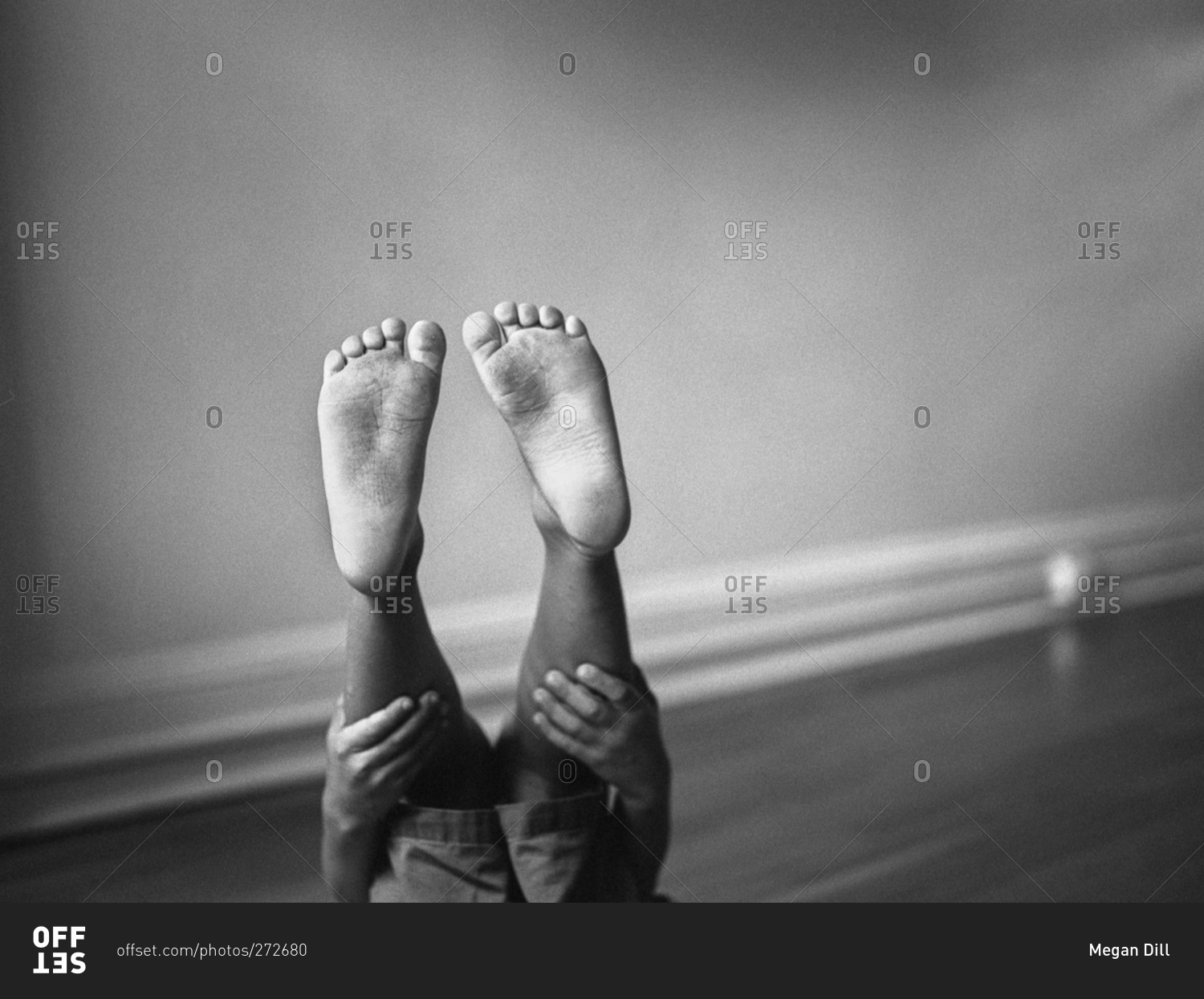 Feet of a little boy holding his legs up in the air stock photo OFFSET