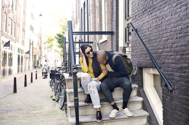 Young couple sitting on a stoop laughing